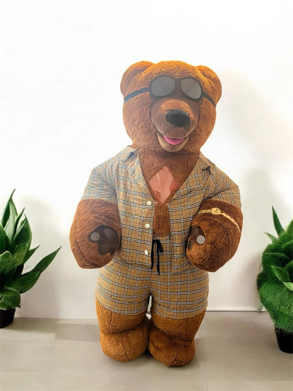 Stuffed teddy bear wearing sunglasses and a plaid shirt with a white background