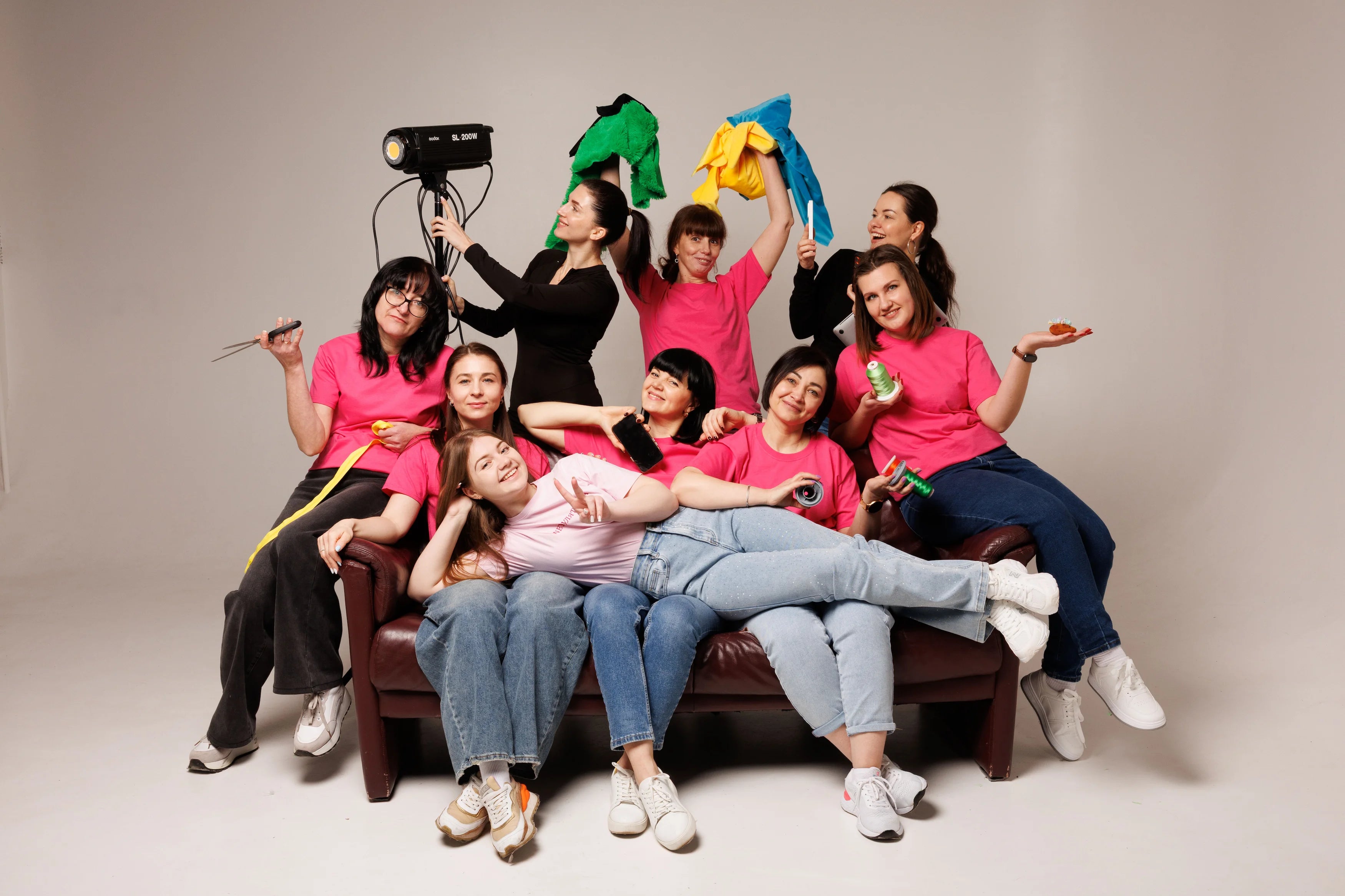 Group of people posing on a couch with colorful props against a plain background