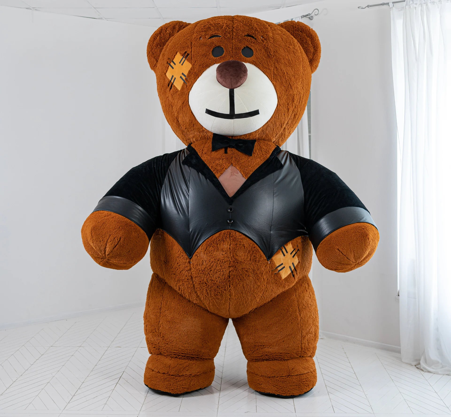 Large teddy bear wearing a black leather outfit on a white background